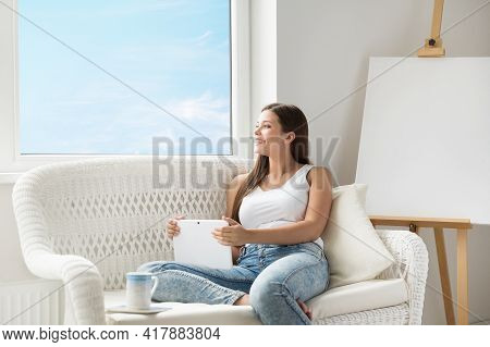 Woman With Tablet Thinking Looking Forward At Home Sofa. Beautiful Girl Dreaming With Touch Pad Next