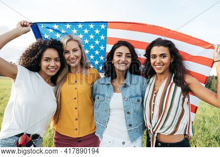 Group Of Multi-ethnic Women Holding A Usa Flag. Female Friends Celebrating Independence Day.