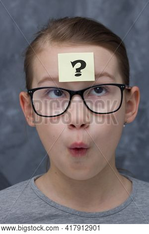 The Girl With Glasses Has A Question Mark On Her Forehead And Is Surprised. Girl In Astonishment Str