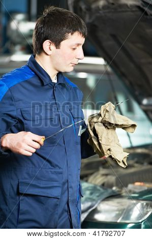 オート メカニック技術者を交換し、自動車の縁起にモーター オイルを注ぐ中レベルを調べる