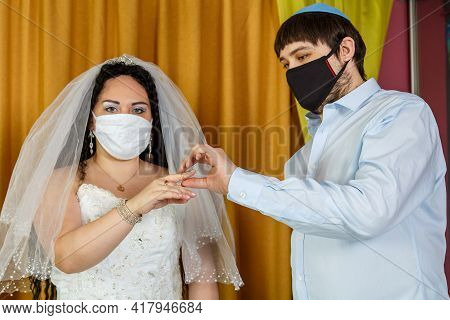 During A Chuppah Ceremony At A Jewish Wedding In A Synagogue, The Groom Puts A Ring On The Bride's I