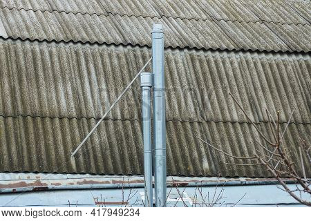 Two Long Metal Gray Chimney Pipes On A Slate Roof