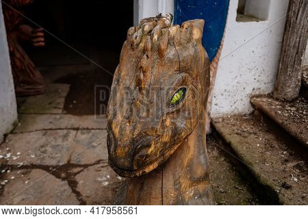 Carved Wooden Statue In The Courtyard, Dragon Head With Yellow Eyes At The Entrance To The Basement,