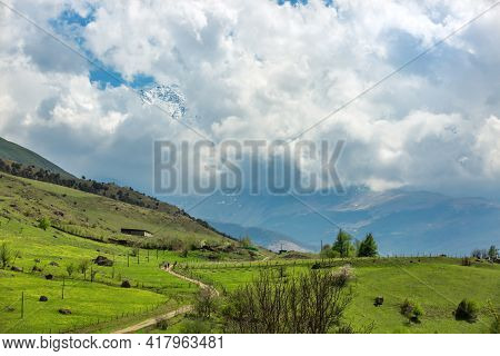 Rural Landscape. Road, Emerald Hills, Tractor. Farm Fields In The Mountains. Village In North Osseti