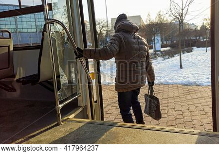 Woman Passenger With Jeans And Coat Jacket With Hand Bag Getting Off The Bus During Winters. Female 