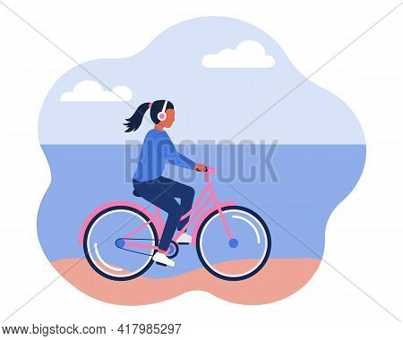 A Girl In Headphones Rides A Bicycle Along The Beach, The Shore. The Concept Of A Healthy Active Lif