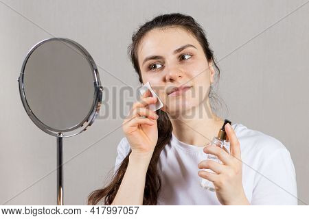 A 25-year-old Woman Holds A Face And Neck Tonic And A Cotton Pad. Anti-wrinkle Skin Care, Vitamins A