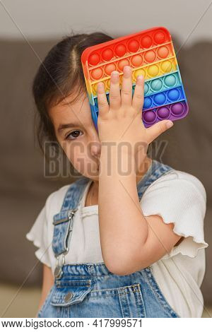 Creative Image With Child Playing Poppit Fidget Toy. Young Little Girl At Home Holding Pop It New Fi