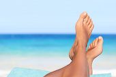 Vacation holidays. Woman feet closeup of girl relaxing on beach on sunbed enjoying sun on sunny summ