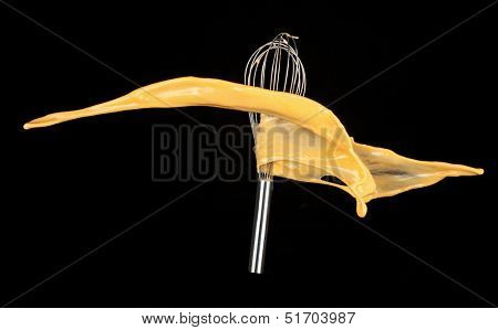 Isolated shot of cracked eggs with egg whip on black background