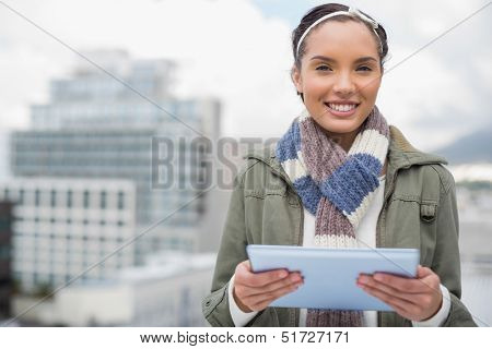Close up of smiling woman using tablet while looking at camera outside