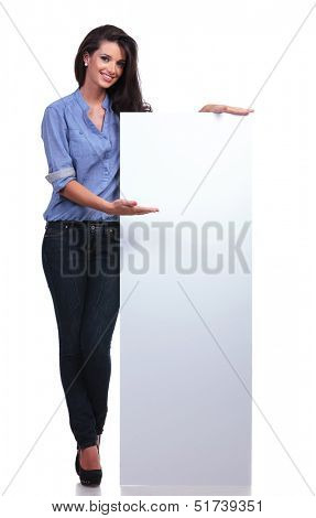 full length picture of a young casual woman presenting a blank pannel and smiling for the camera. on white background