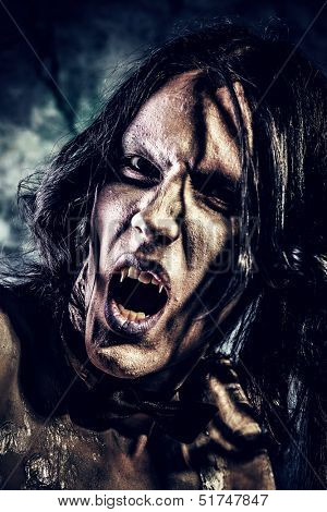 Close-up portrait of a gloomy vampire standing at the night background. Halloween.