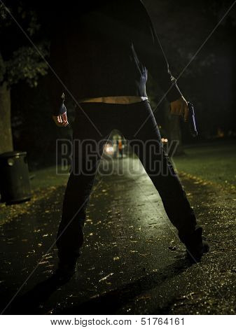 Man treating two women with a gun at night