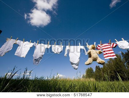 Baby Clothing and a teddybear on a clothesline towards blue sky