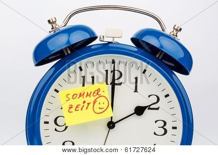 an alarm clock with a note as a reminder to the uhrumstellung at summer time