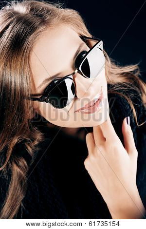 Close-up portrait of a smiling young lady with beautiful hair wearing black sunglasss.