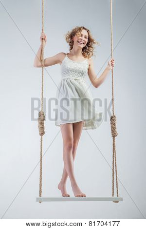Young loughing bare-footed girl on swing