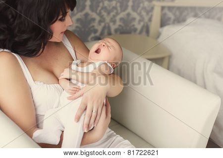 Young mother holds a baby yawning in her sleep.