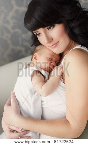Young mother with a sleeping baby in her arms.