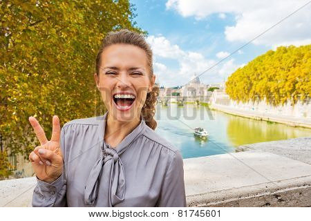 Portrait Of Happy Young Woman Showing Victory Gesture While Stan
