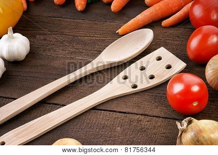Wooden kitchenware with vegetables on a wooden background