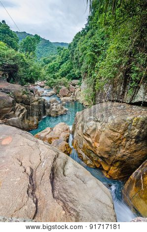 Jungle waterfall with flowing water, large rocks