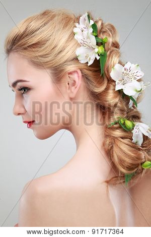 Beautiful girl, isolated on a light - grey background with varicoloured flowers in hairs, emotions, cosmetics