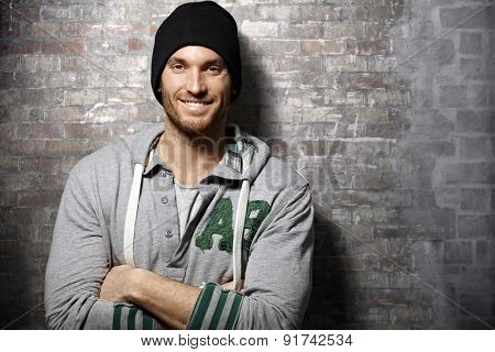 Portrait of happy young casual man standing over brick wall