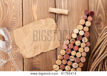 Wine bottle shaped corks, wine glass and corkscrew over rustic wooden table background. Top view with copy space