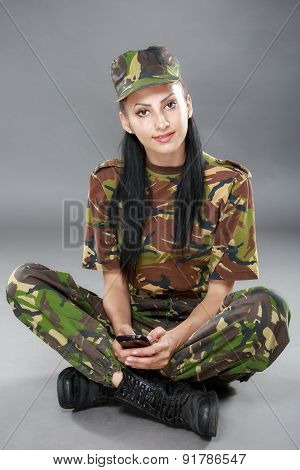 happy woman soldier looks at a mobile phone