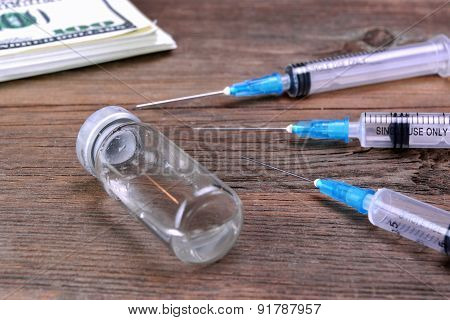 Money Wad, Syringe And Vial On Rough Wood Table