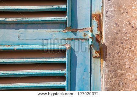 A blue wood window with a rusty hinge