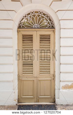 An old weathered french window with closed shutters