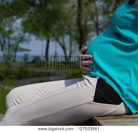 Round big belly of a pregnant woman in the park recreation rehabilitation