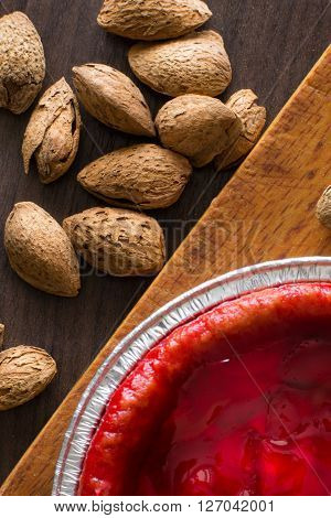 overhead view on fresh strawberry pie with nuts on side and frozen berries. Strawberry cake on dark table. Dark and moody style. Magic moon and mistic light