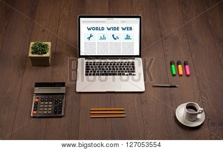 Laptop computer on wooden desk with office suplies