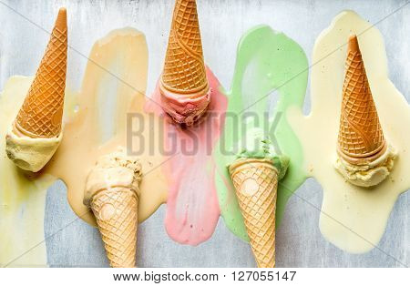 Colorful ice cream cones of different flavors. Melting scoops. Top view, steel metal background