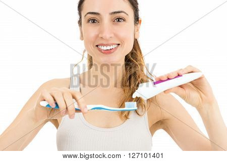 Caucasian woman papplying toothpaste to teethbrush to brush her teeth. Isolated on white background.