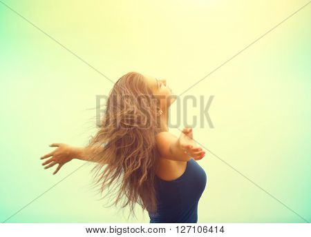 Free Happy Woman Enjoying Nature. Beauty Girl raising hands Outdoor. Freedom concept. Beauty Girl over Sky and Sun. Sunbeams. Enjoyment