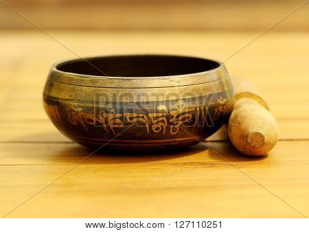 Tibetan singing bowl made of brass on teak wood table.