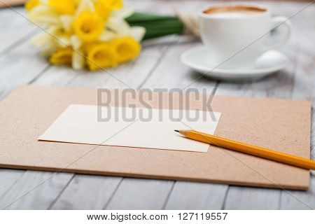 A cup of coffee next to the spring white flowers on wooden texture. Space for text.