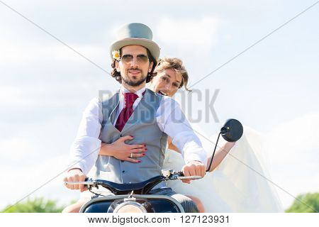 Wedding groom and bride driving motor scooter having fun 