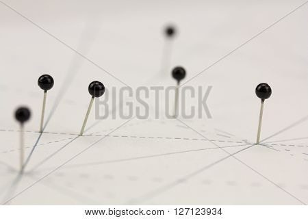 Black Pins In Paper Linked By Lines