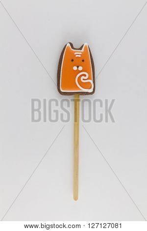 cookies in the shape of a red fox on a wooden stick , shot on a white background . one subject in the frame.