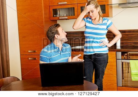 Man watching something on laptop, his wife is angry