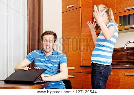 Man watching something on laptop, his wife is angry