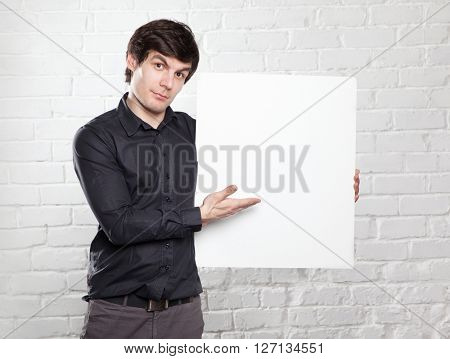 young man holding poster in brick room