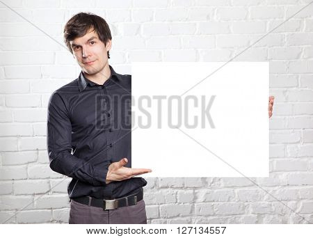 young man holding poster in brick room