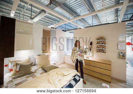 PARIS FRANCE - APR 12 2016: Elegant woman choosing bedroom furniture in the design store interior of IKEA furniture mall in PAris France